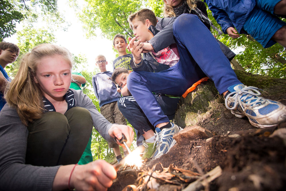 Eine Schülerin entzündet ein Lagerfeuer: Freizeitaktivitäten im Ferien-Lerncamp
